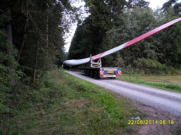 Transport eines überlangen Rotorblatts durch Waldgebiet zum Bürgerwindpark Bernhardswinden – zeigt logistische Herausforderungen beim Ausbau erneuerbarer Energien.